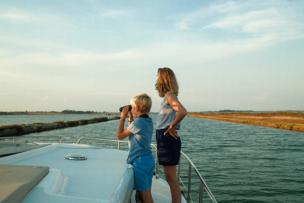 A child looking through binoculars from the bow of a licence-free boat